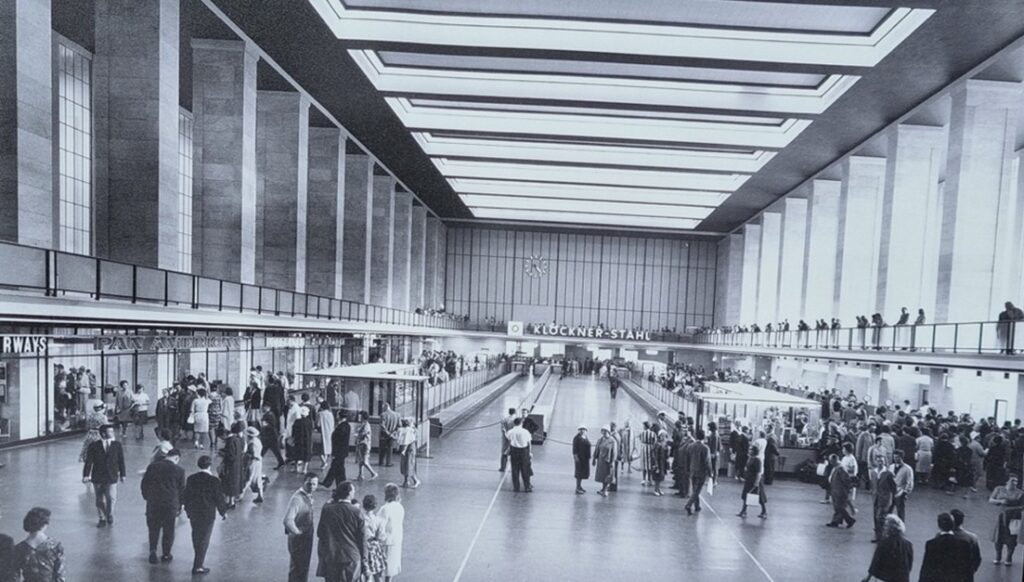 Historisches Foto der Abflughalle in Berlin-Tempelhof: großer Innenraum mit Oberlicht, vielen Besuchern und Schaltern entlang der Seiten.